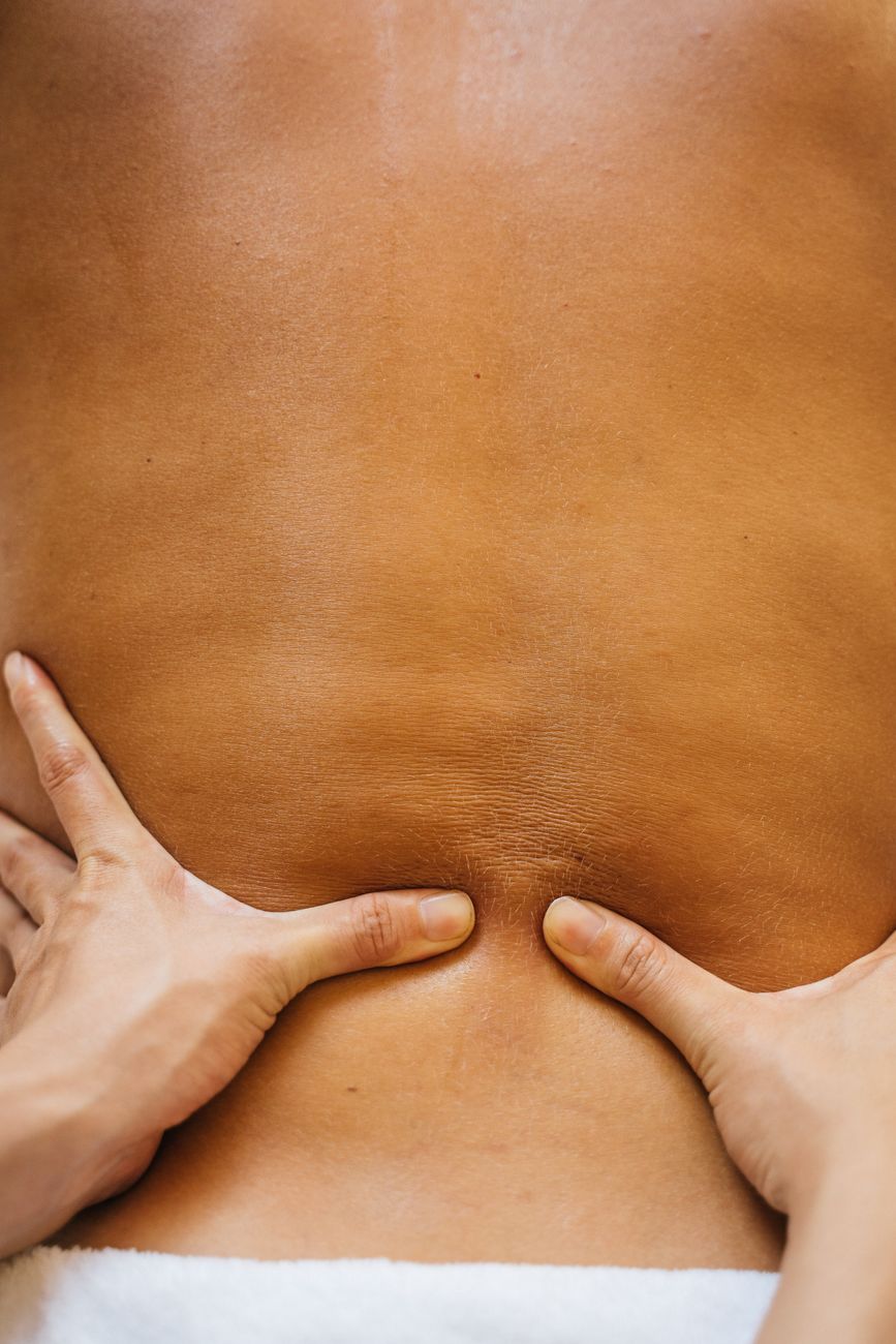 Zblízka ruky terapeuta počas masáže chrbta klienta.