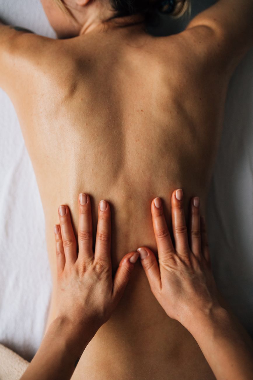 Ruky terapeuta pri uvoľňujúcej masáži chrbta v pokojnom prostredí.